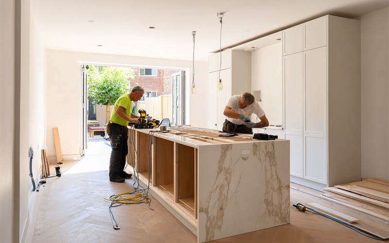 Two tradesmen working on a kitchen renovation with a marble-look island bench