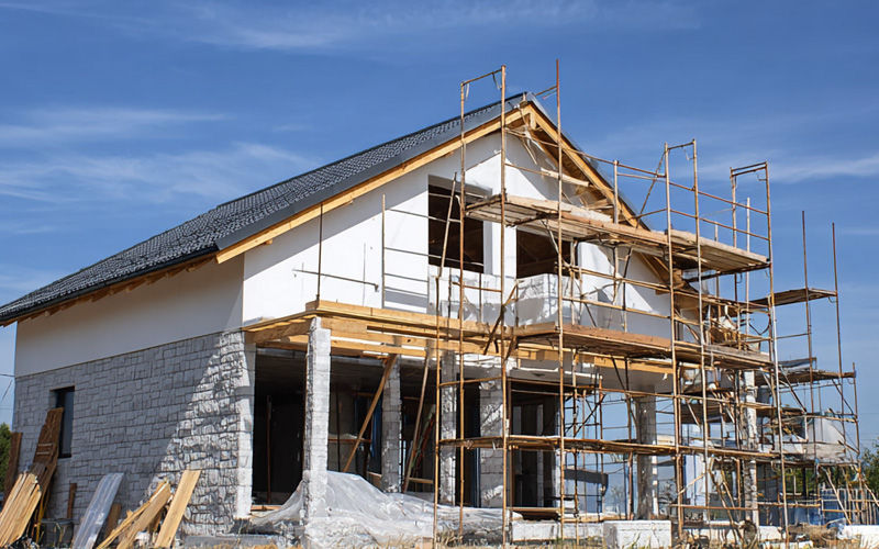 Rendered two-storey house wrapped in scaffolding during construction